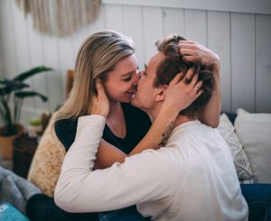 couple snuggling and kissing on their bed